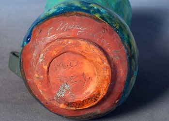 Orange-red base of a blue-green Doull vase, with incised MD PEI lettering and a pencilled Aunt Mary Doull note.