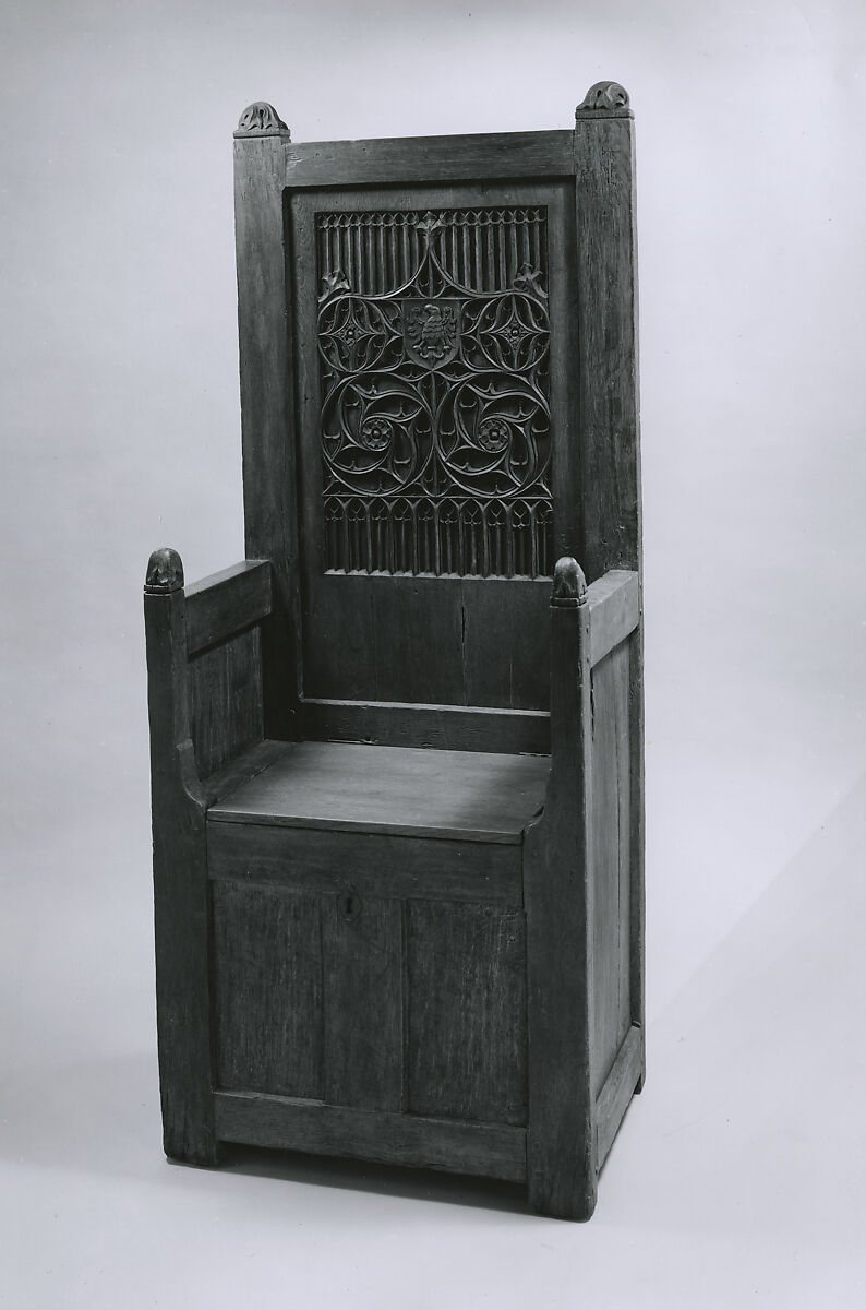 Black-and-white photograph of a tall oak chair with a carved Gothic back and a plain seat documented as a replacement