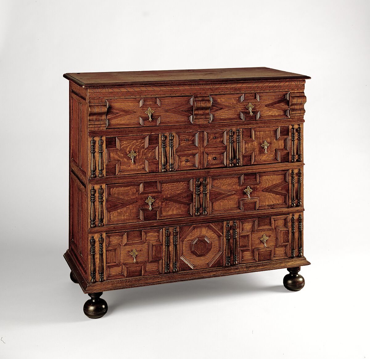 Wooden chest with four drawers, geometric applied mouldings, turned ornaments and brass handles
