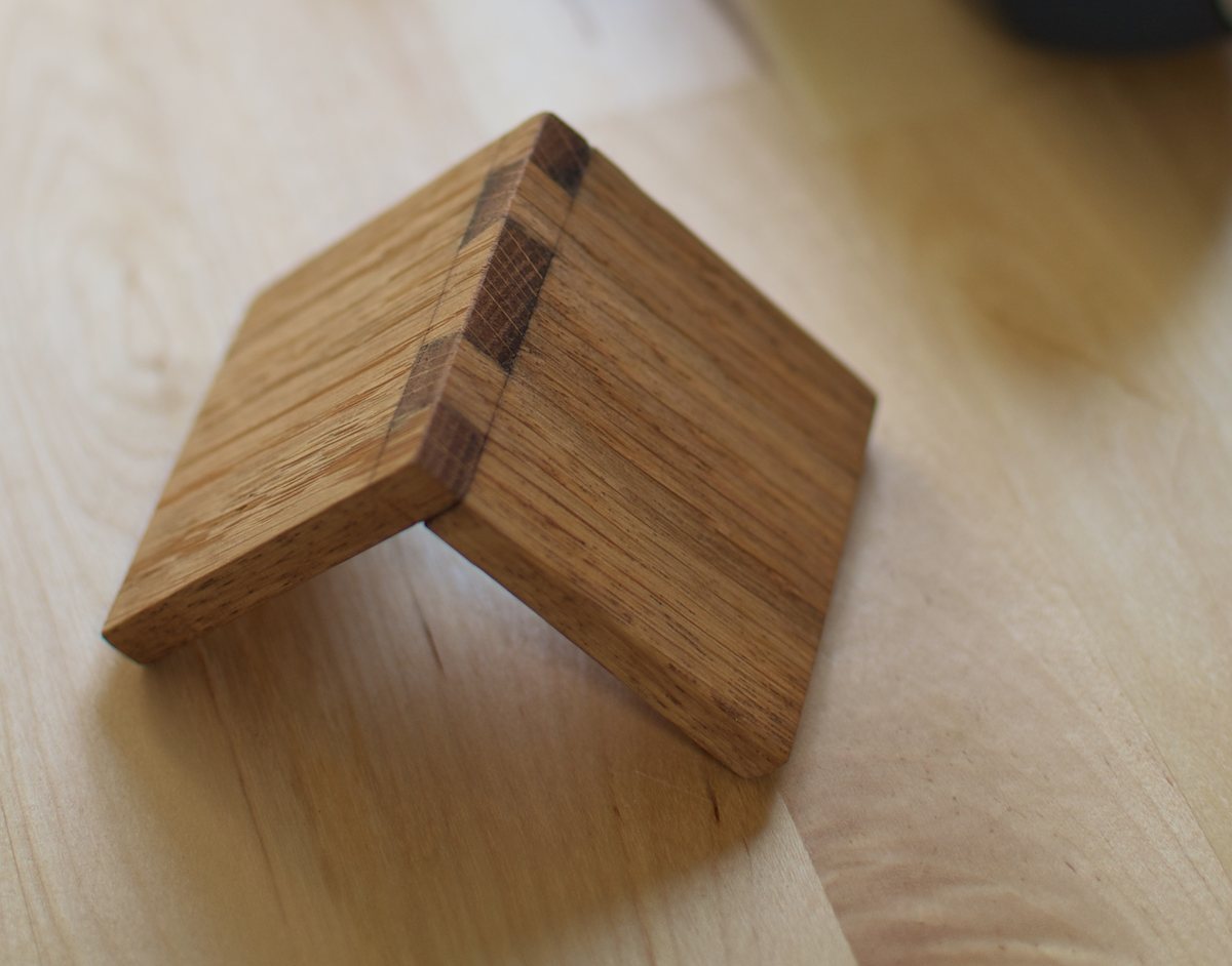 Two small oak boards joined at a right angle with hand-cut dovetails on a modern workbench