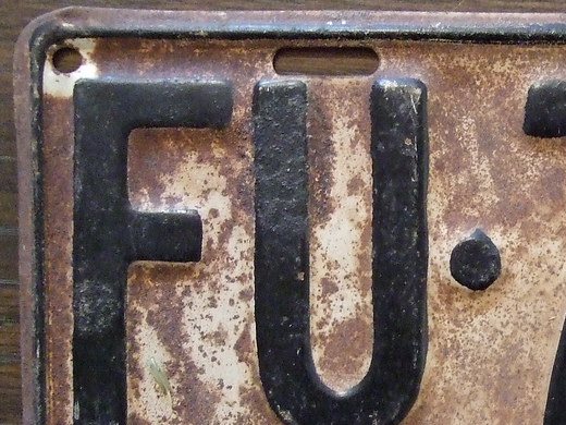 Detail of rust, worn paint and a mounting hole on a 1930 Ontario licence plate